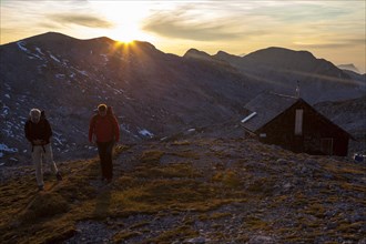 Two hikers at Edelweisserhuette refuge at sunset