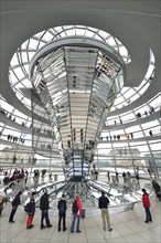 Visitors in the interior with the mirrored central column of the dome of the Reichstag Building