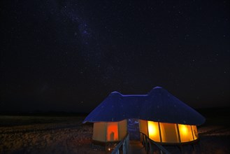 Illuminated chalet or cabin of the Sossus Dune Lodge at night