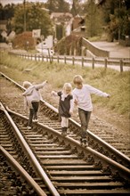 Three children walking on railway lines