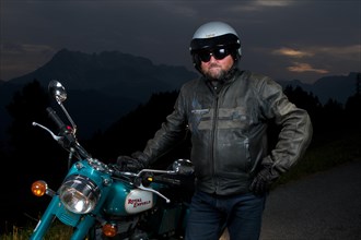 Motorcycle rider standing next to his motorbike