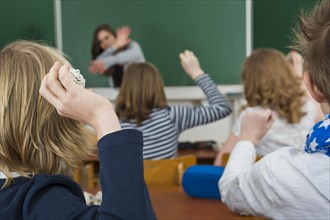School children in a classroom throwing paper balls at the teacher