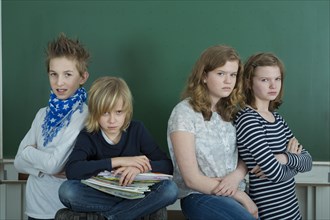 Four grumpy school children in a classroom