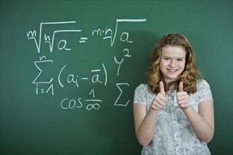 Schoolgirl standing in front of a school blackboard with mathematical formulas