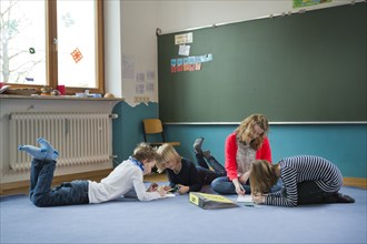 Students at an independant school sitting and lying to work on the ground