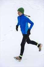 Female jogger on a run in winter in the snow