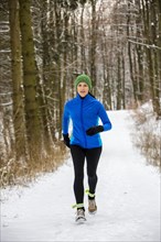 Female jogger on a run in a snow-covered forest