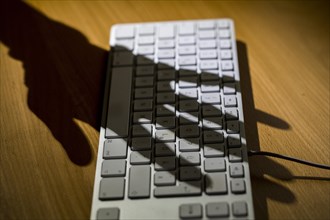Shadow of a hand on a computer keyboard