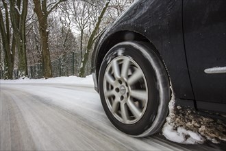Car with winter tyres driving on a road covered with snow