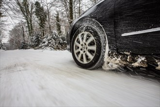 Car with winter tyres driving on a road covered with snow