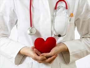 Female doctor holding a red heart in her hands