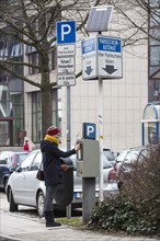 Woman purchasing a parking ticket from a solar powered parking ticket vending machine