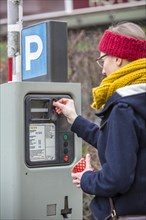 Woman purchasing a parking ticket from a parking ticket vending machine