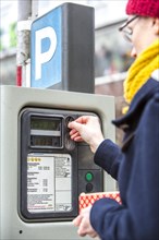Woman purchasing a parking ticket from a parking ticket vending machine