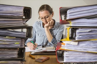 Woman working at a desk between stacks of files