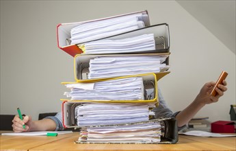 Woman working at a desk behind a stack of files