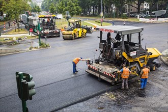 Rolling machine and asphalt spreaders during asphalt work on a large urban road construction site