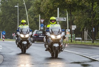 Policemen wearing yellow helmets on motorcycles