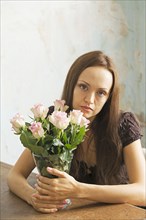 Young woman sitting at a table with flowers in a vase
