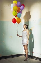 Young woman holding balloons in a empty room