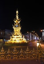 The illuminated golden clock tower in the town center at night