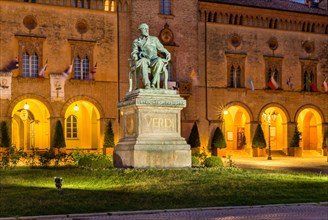 Illuminated Verdi monument in front of Rocca Pallavicino with Opera House Teatro Guiseppe Verdi