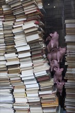 Stacked books and decorative pigs in a shop window