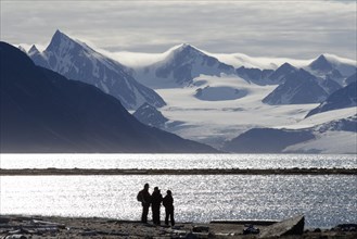 Silhouettes of expedition participants in front of the mountain and glacier scenery of Smeerenburgbreen