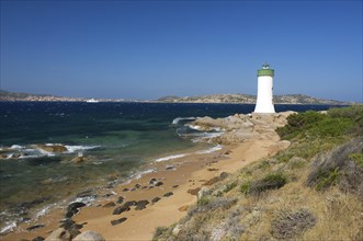 Beach of Porto Faro with the lighthouse at Capo d'Orso