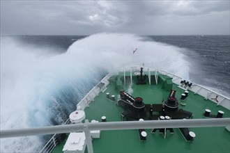 A huge wave is breaking over the bow of the expedition cruise ship MS Expedition in the Drake Passage