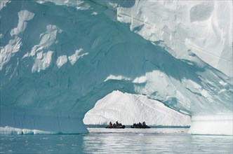 Zodiac inflatable boats seen through the arch of a large iceberg