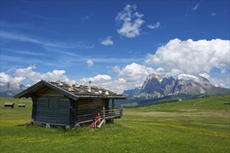 Woman sitting at an alpine hut in front of Piatto Mountain and Sasso Lungo Mountains