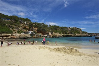 Tourists on the beach in the bay at Cala Llombards