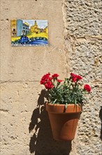 Holy image and a flower pot on a house wall