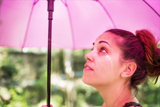 Young woman with a pink umbrella in the sun
