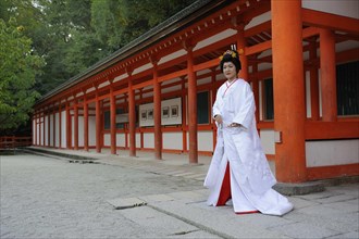 Bride in a traditional kimono with brocade holding a fan