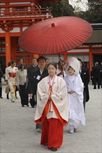 Japanese woman wearing scarlet hakama pants and a white kimono shirt with lengthy sleeves