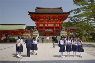 Female pupils are standing outside the gatehouse of the Fushimi Inari Taisha Shinto shrine