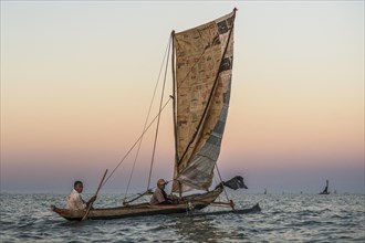 Fishermen at sunrise in traditional Pirogue outrigger boat on the Indian Ocean