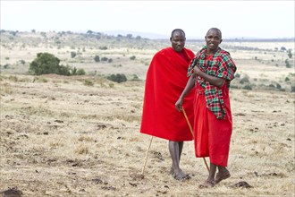 Two Maasai warriors wearing traditional dress in the savannah