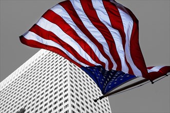 U.S.-American flag flying in front of a skyscraper