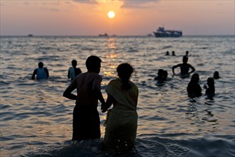 Hindu pilgrims taking a holy bath in the sea at sunrise