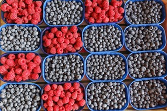 Blueberries and raspberries in bowls at a market stall