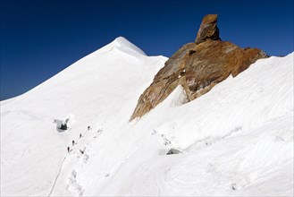 Mountain climbers climbing along the ridge of Zufallspitze Mountain towards Monte Cevedale