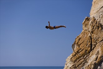 Clavadista or cliff diver jumping off the cliffs of La Quebrada