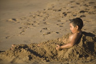 Young covering himself with the sand on the beach