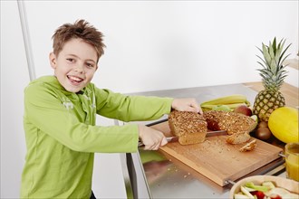 Boy cutting slices off a whole wheat bread