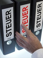 Hand reaching for file folders labeled 'Steuer'