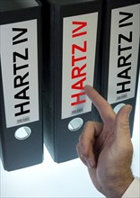 Hand pointing to a ring binder labeled Hartz IV