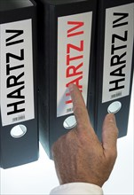 Hand pointing to a ring binder labeled Hartz IV